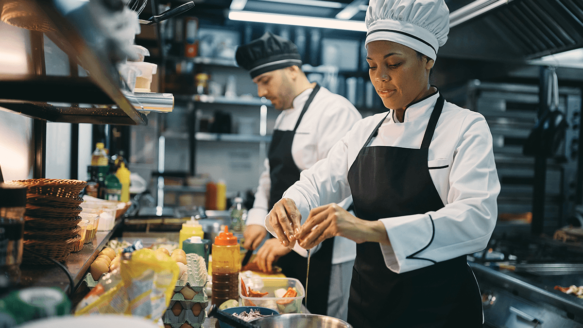 Two chefs cooking in a restaurant kitchen preventing food waste | SkyTab | Shift4